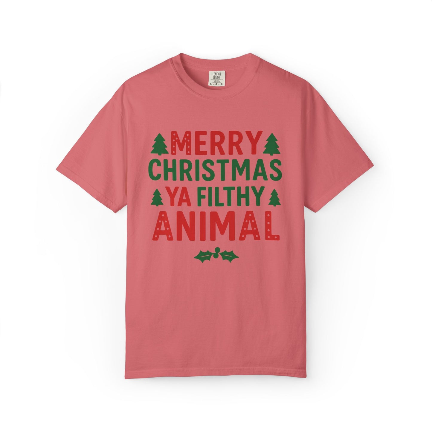 A pink short-sleeve crewneck t-shirt with a festive Christmas graphic that reads 'MERRY CHRISTMAS YA FILTHY ANIMAL' in red and green lettering, accented with small green pine trees and holly leaves, shown on a plain white background.