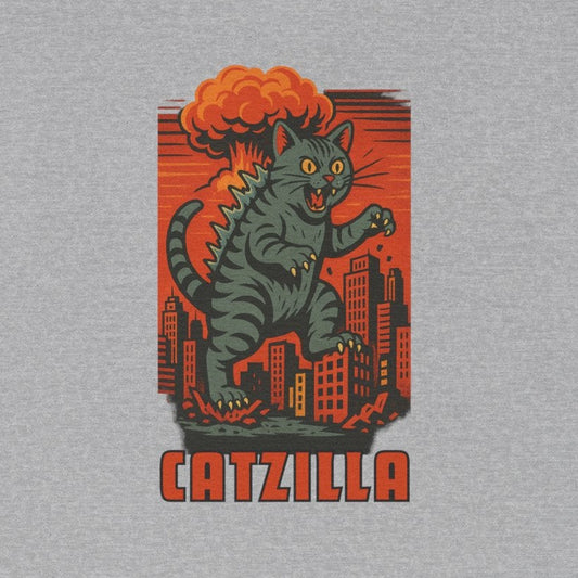 A heather gray short-sleeve crewneck t-shirt featuring a retro-style graphic of a green cat-like monster with orange hair standing in front of a red cityscape, with the word 'CATZILLA' printed below.