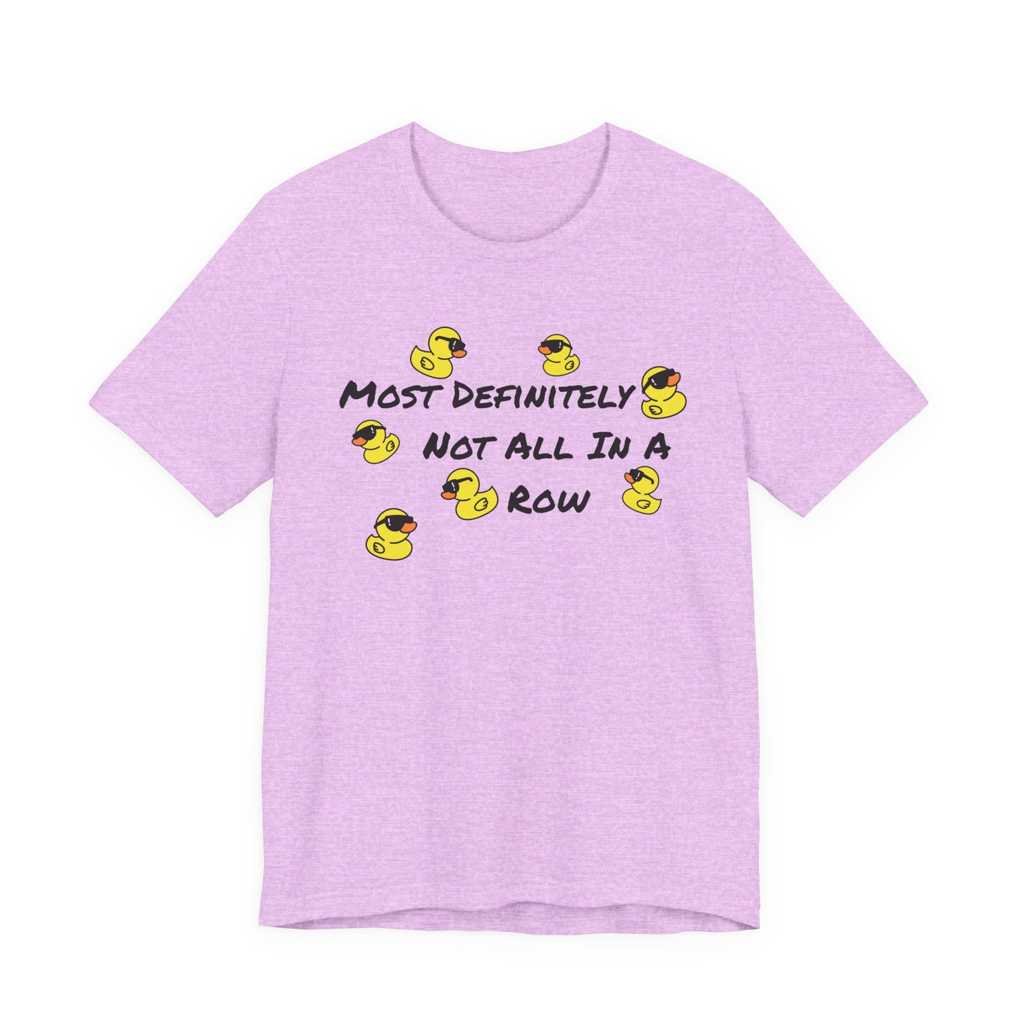 A light purple heather short-sleeve t-shirt with a graphic print on the front. The graphic features the text 'MOST DEFINITELY NOT ALL IN A ROW' in black, surrounded by small yellow rubber ducks wearing sunglasses.