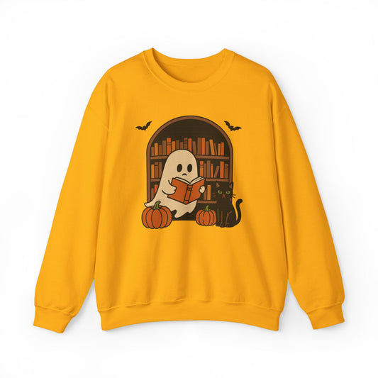 A yellow crewneck sweatshirt featuring a Halloween graphic of a ghost reading a book in front of a bookshelf, with pumpkins, a black cat, and bats.