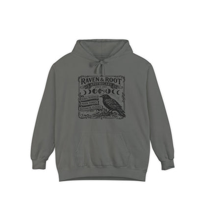 A dark gray pullover hoodie with a vintage-style black graphic on the chest featuring a raven and the text 'Raven & Root Apothecary' and 'Morbilia'.