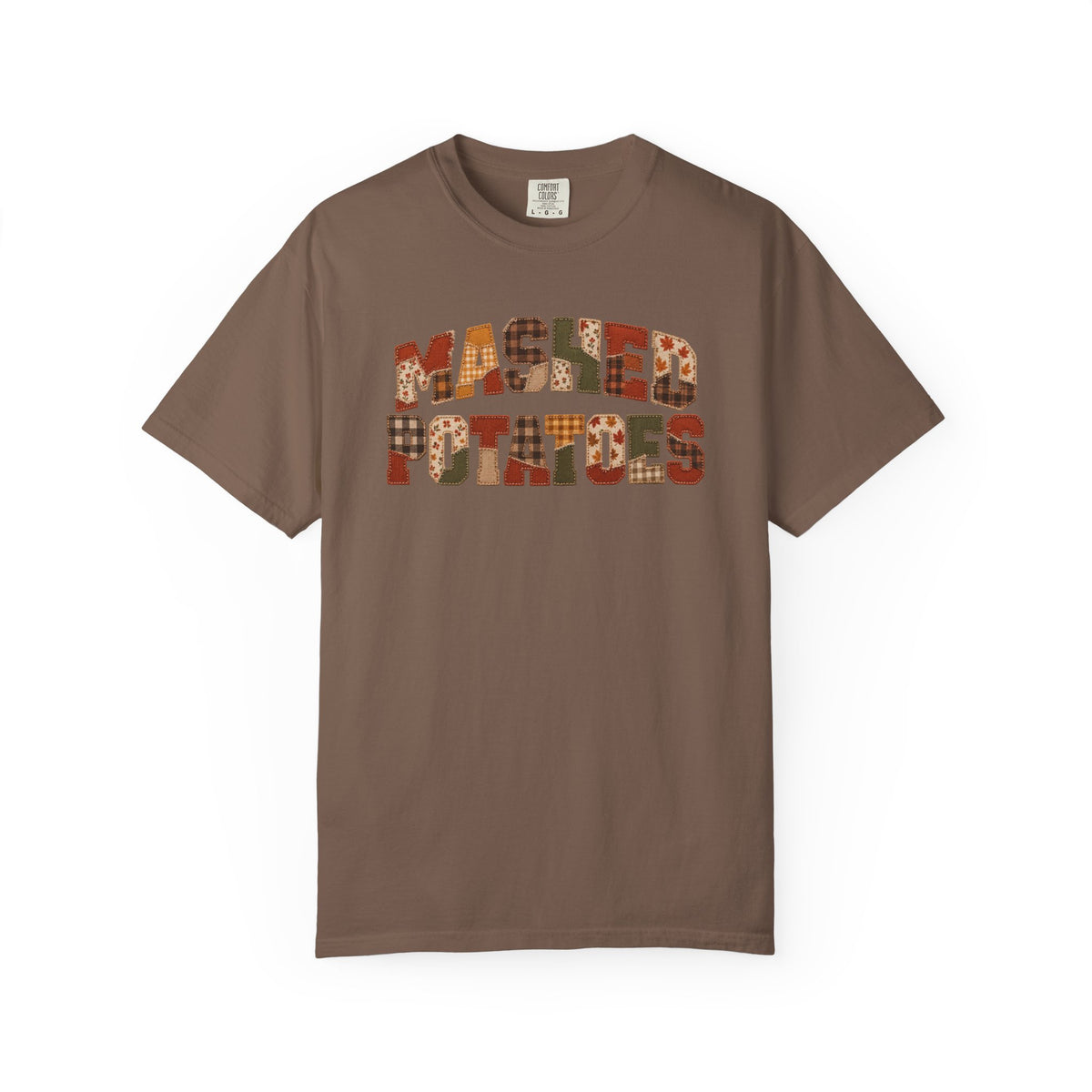 A brown short-sleeve crewneck t-shirt featuring a graphic on the chest that reads 'MASKED PATRIOTS' in a patchwork pattern of autumn colors like orange, red, and brown plaid.