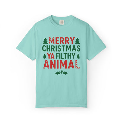 A light blue-green crewneck t-shirt with a festive graphic print reading 'MERRY CHRISTMAS YA FILTHY ANIMAL' in red and green lettering, accented with small pine tree icons, shown on a plain white background.