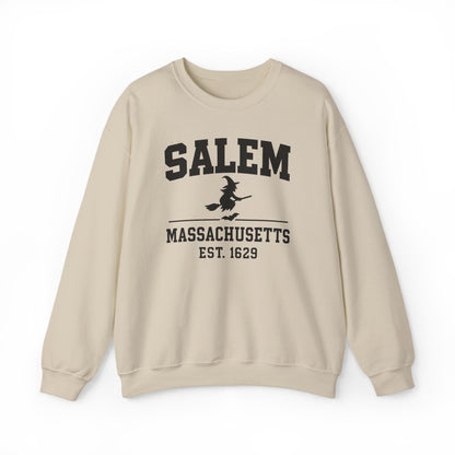 A beige crewneck sweatshirt with a black graphic print on the front reading 'SALEM MASSASETTS EST. 1629' with a witch riding a broomstick, shown against a plain white background.