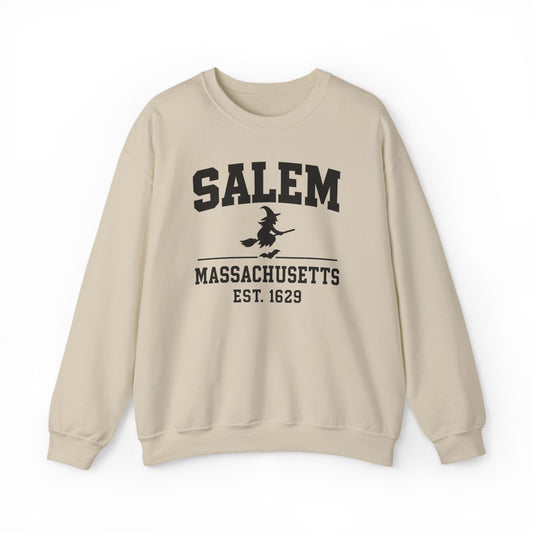 A beige crewneck sweatshirt with a black graphic print on the front reading 'SALEM MASSASETTS EST. 1629' with a witch riding a broomstick, shown against a plain white background.