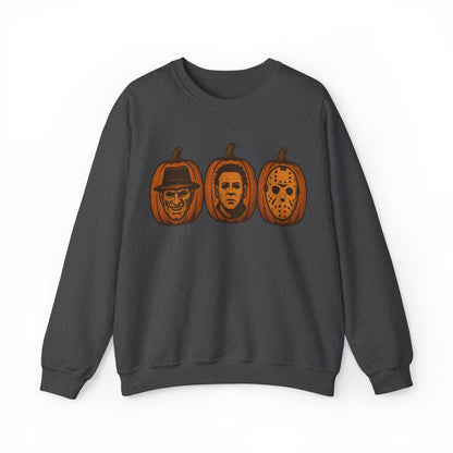 A dark gray crewneck sweatshirt featuring a graphic print of three orange pumpkins carved with faces resembling iconic horror movie villains, shown against a plain white background.