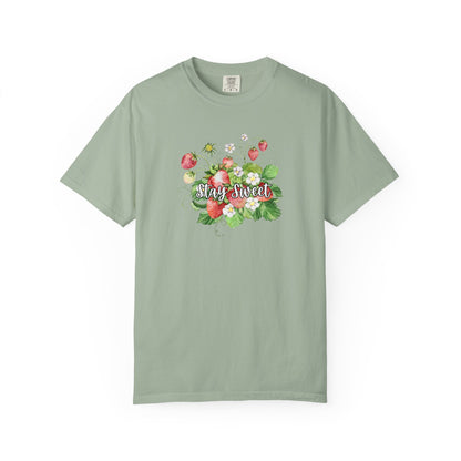 A sage green short-sleeve t-shirt with a colorful floral graphic on the chest featuring strawberries, green leaves, and the text 'Stay Sweet' in cursive, displayed on a clean white background.