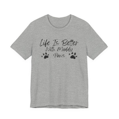 A heather gray short-sleeve t-shirt with a black graphic print on the front that reads 'Life Is Better With Muddy Paws' alongside two paw prints, shown against a plain white background.