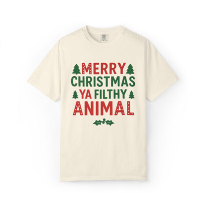 An off-white crewneck t-shirt with a festive graphic print reading 'MERRY CHRISTMAS YA FILTHY ANIMAL' in red and green text with small pine tree and holly accents, displayed on a clean white background.