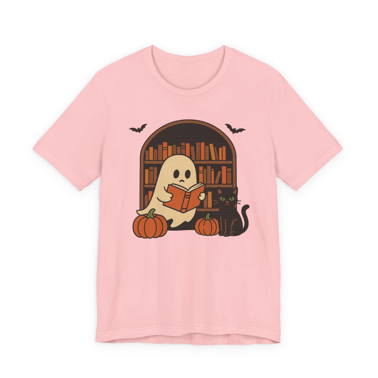 A light pink short-sleeve t-shirt with a cartoon graphic of a ghost reading a book in front of a bookshelf, with pumpkins, a black cat, and bats.