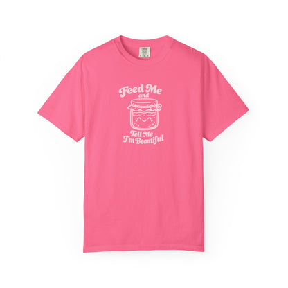 A pink short-sleeve crewneck t-shirt with a white graphic print on the front. The graphic features a cute cartoon jar filled with food and the text 'Feed Me and Tell Me I'm Beautiful' written around it.