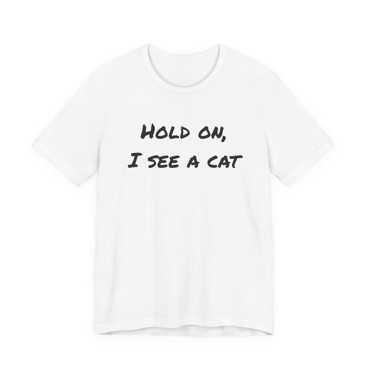 A white short-sleeve crewneck t-shirt with the text 'HOLD ON, I SEE A CAT' printed in a black handwritten-style font across the chest, displayed on a solid white background.