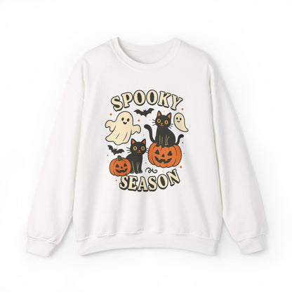 A white crewneck sweatshirt featuring a colorful Halloween graphic with the text 'SPOOKY SEASON' and illustrations of ghosts, black cats, pumpkins, and bats.