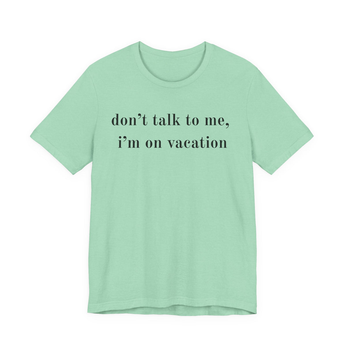 A mint green short-sleeve t-shirt with the text 'don't talk to me, i'm on vacation' printed in black serif font across the chest, displayed on a solid white background.
