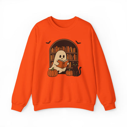 An orange crewneck sweatshirt featuring a Halloween graphic of a cute cartoon ghost reading a book in front of a bookshelf, with pumpkins, a black cat, and bats.