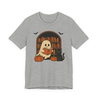 A heather gray short-sleeve t-shirt with a graphic of a cute cartoon ghost reading a book in front of a bookshelf, accompanied by pumpkins, a black cat, and bats.