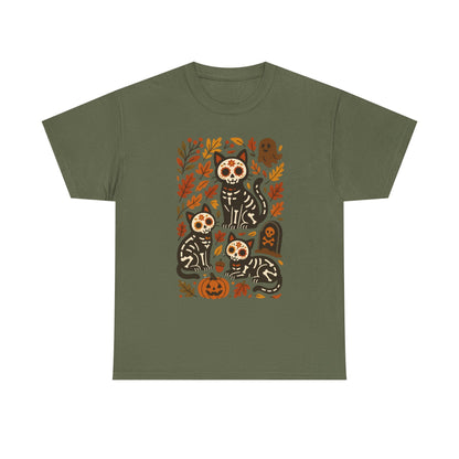 An olive green short-sleeve crewneck t-shirt featuring a colorful graphic print of three black and white sugar-skull cats surrounded by autumn leaves, pumpkins, and tombstones.