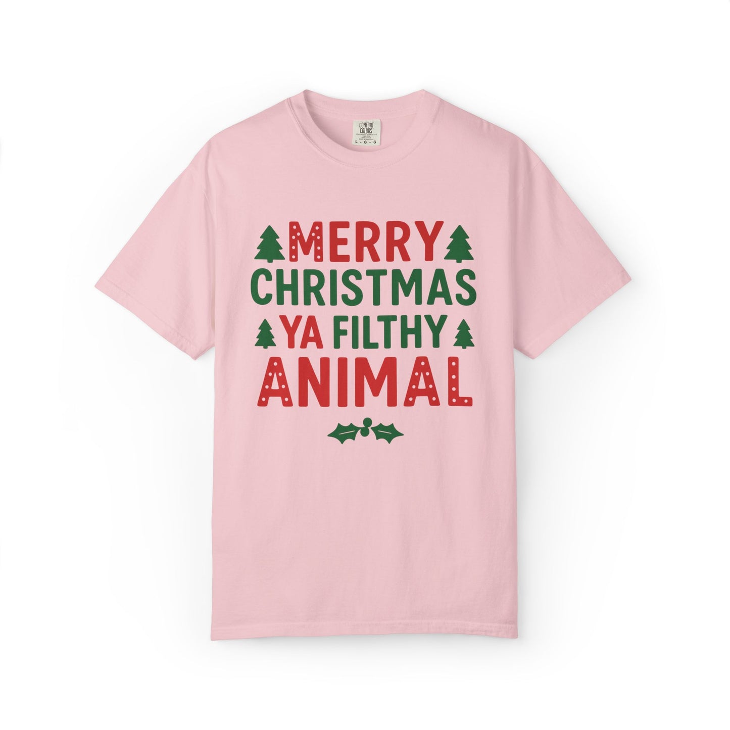 A light pink short-sleeve crewneck t-shirt with a festive graphic on the chest that reads 'MERRY CHRISTMAS YA FILTHY ANIMAL' in red and green lettering, accented with small green pine trees and holly leaves, shown on a plain white background.