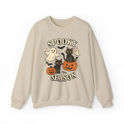 A beige crewneck sweatshirt featuring a 'Spooky Season' Halloween graphic with cartoon ghosts, black cats, pumpkins, and bats on a white background.