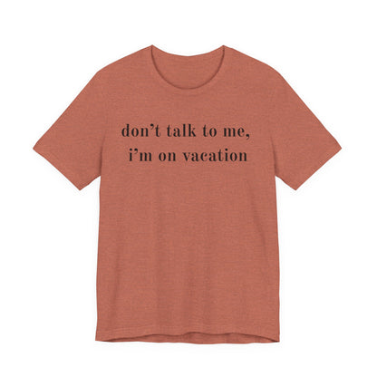 A heathered terracotta short-sleeve t-shirt with the text 'don't talk to me, i'm on vacation' printed in black serif font across the chest, displayed on a solid white background.