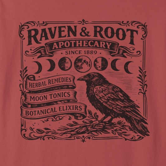 A dusty red short-sleeve t-shirt with a black graphic print on the front featuring a raven, moon phases, and the text 'Raven & Root Apothecary'.