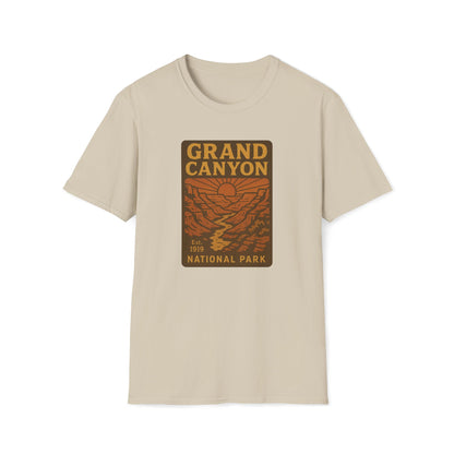 A beige crewneck t-shirt featuring a rectangular graphic print on the chest that reads 'GRAND CANYON NATIONAL PARK' in yellow and brown over an orange canyon landscape illustration.