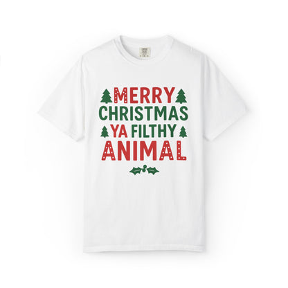 A white short-sleeve crewneck t-shirt featuring a festive Christmas graphic on the front that reads 'MERRY CHRISTMAS YA FILTHY ANIMAL' in red and green lettering with small pine tree illustrations.