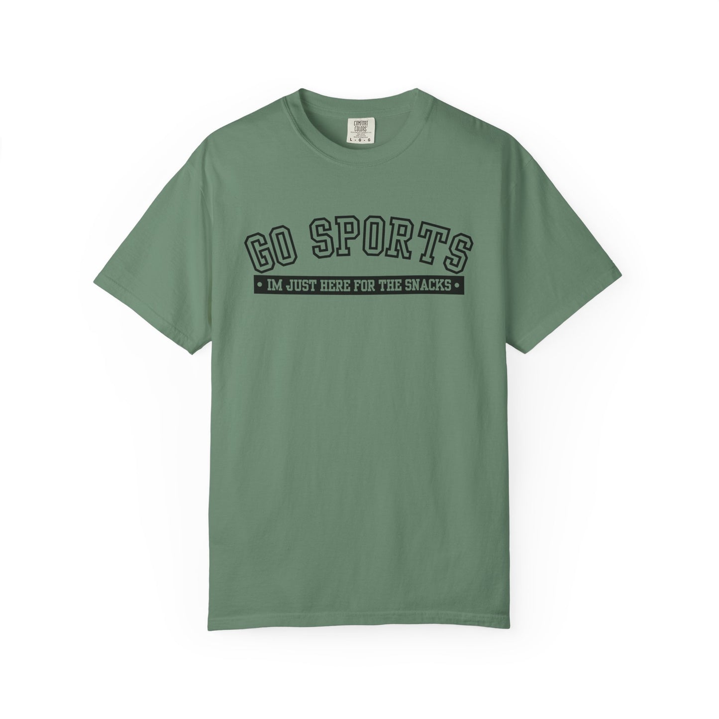 A sage green short-sleeve t-shirt with a black graphic print on the chest reading 'GO SPORTS' and 'I'M JUST HERE FOR THE SNACKS'.