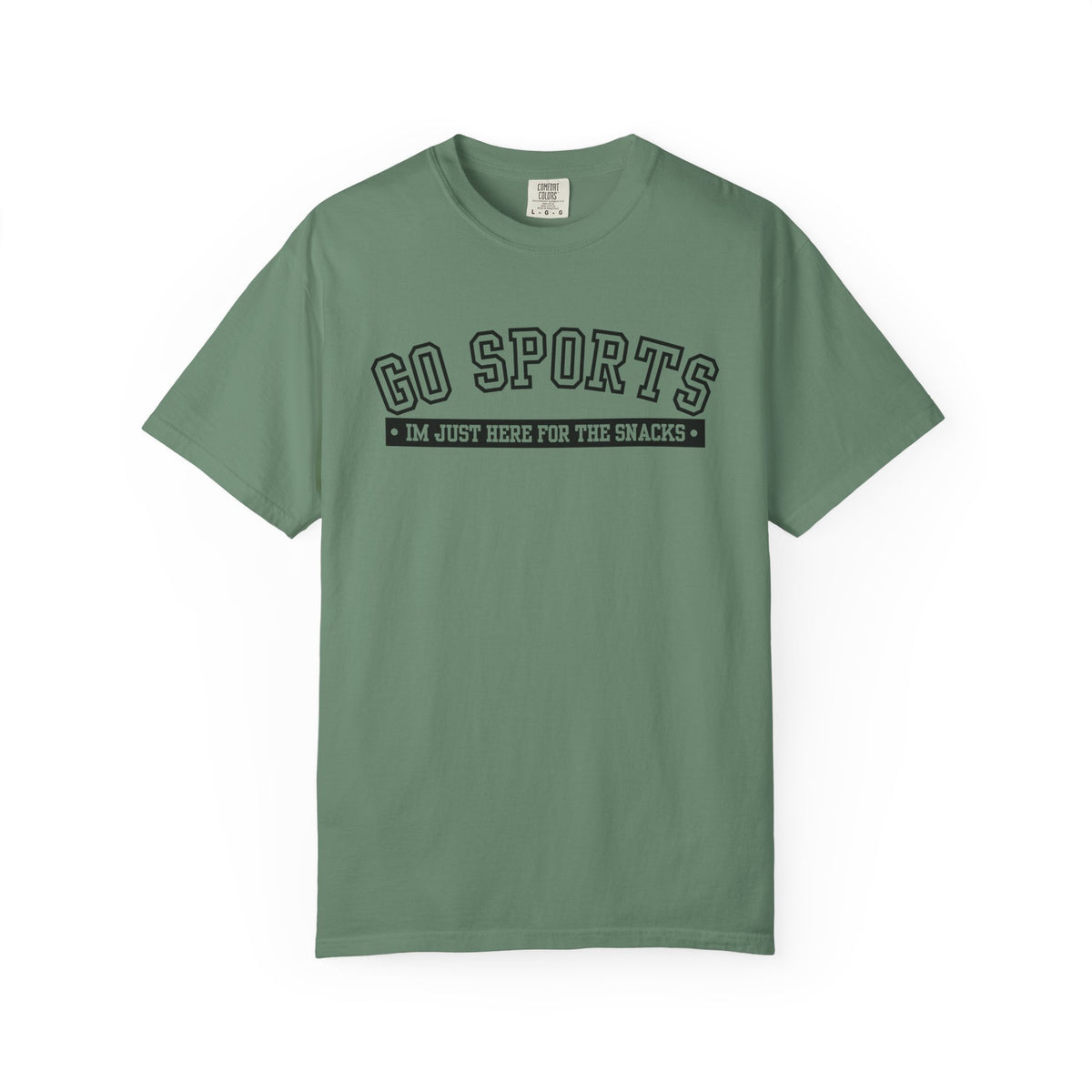 A sage green short-sleeve t-shirt with a black graphic print on the chest reading 'GO SPORTS' and 'I'M JUST HERE FOR THE SNACKS'.