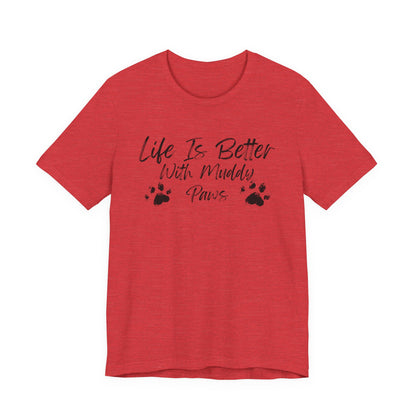 A heather red short-sleeve t-shirt with a black graphic print on the front that reads 'Life Is Better With Muddy Paws' alongside two paw prints, shown against a plain white background.