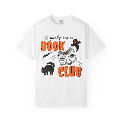 A white short-sleeve crewneck t-shirt featuring a 'spooky season BOOK CLUB' graphic on the front with illustrations of a black cat, ghost, bat, and a book.