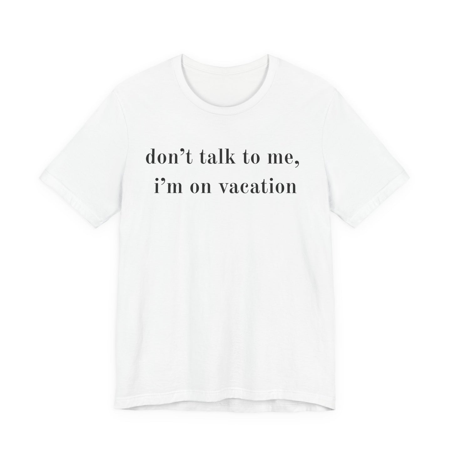 A white short-sleeve crewneck t-shirt with the text 'don't talk to me, i'm on vacation' printed in black serif font across the chest, displayed on a clean white background.