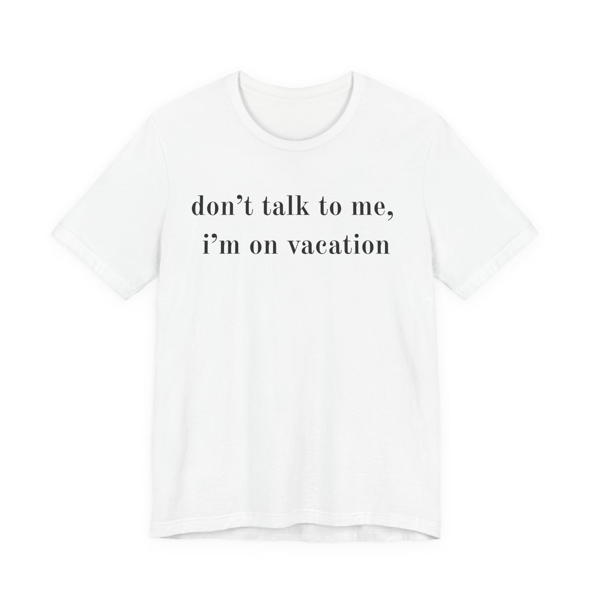 A white short-sleeve crewneck t-shirt with the text 'don't talk to me, i'm on vacation' printed in black serif font across the chest, displayed on a clean white background.
