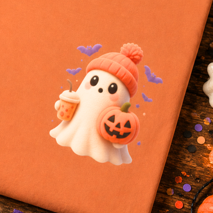 A close-up of an orange gift box decorated with a cute 3D clay-style Halloween ghost sticker. The ghost wears an orange knit hat with a pom-pom, holds a jack-o'-lantern pumpkin, and has a small drink cup.